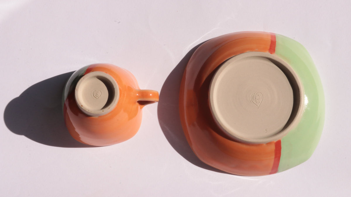 ceramic cup and saucer with colorful glaze on a white background