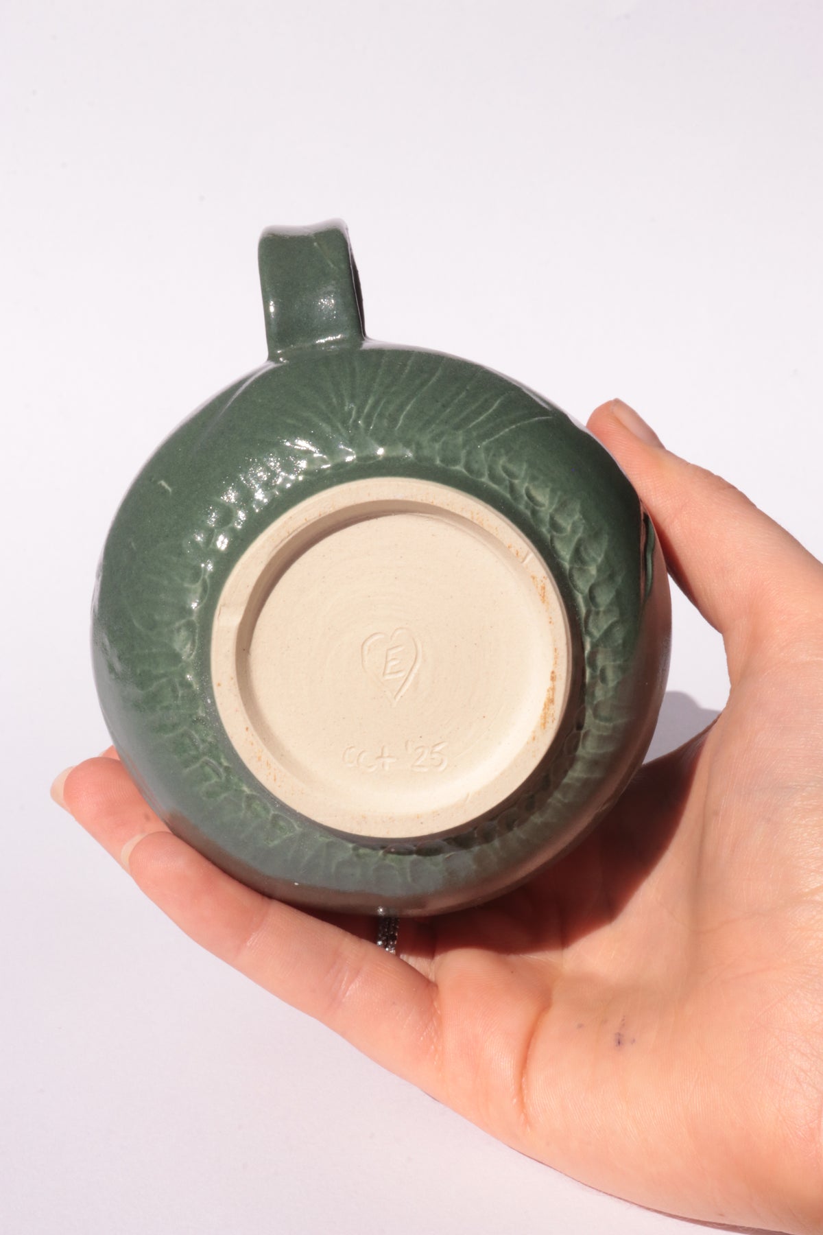 Dark green mug with subtle engraved design on a white background