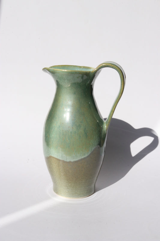 Green ceramic pitcher on a white background