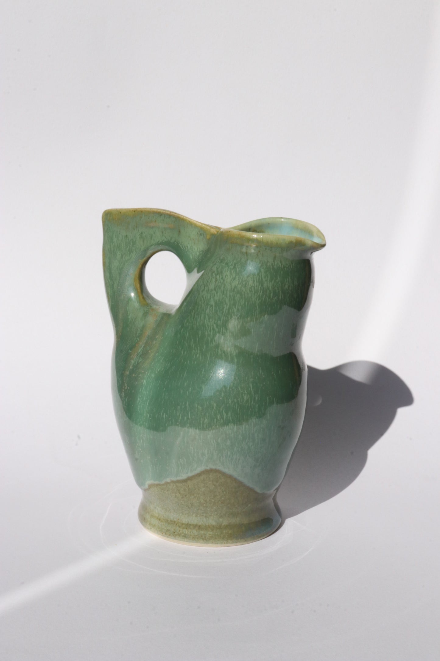Green ceramic jog with integrated handle and spout