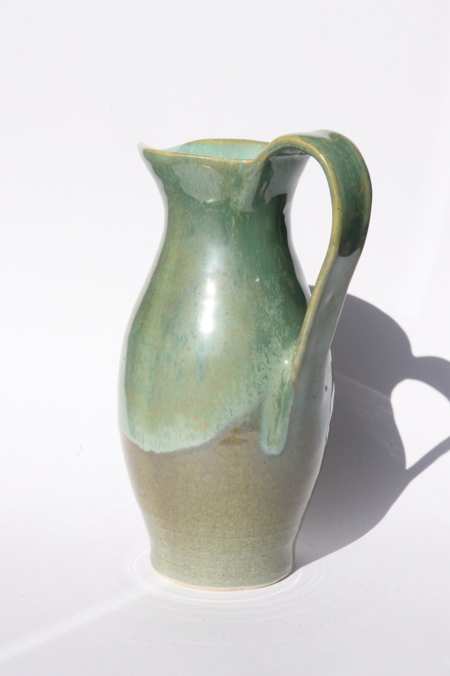 Green ceramic pitcher on a white background