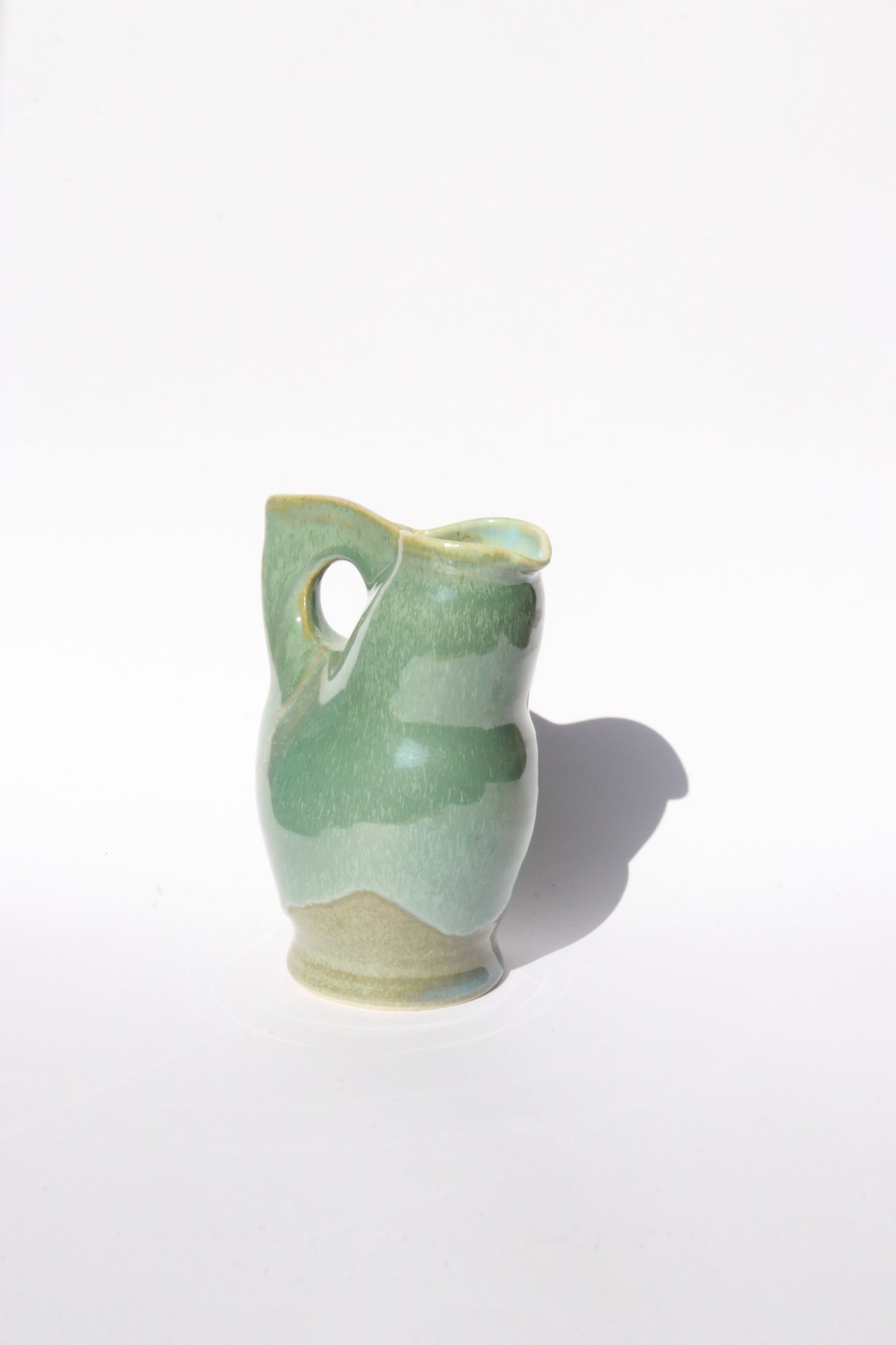 Green ceramic vase with a unique design on a white background