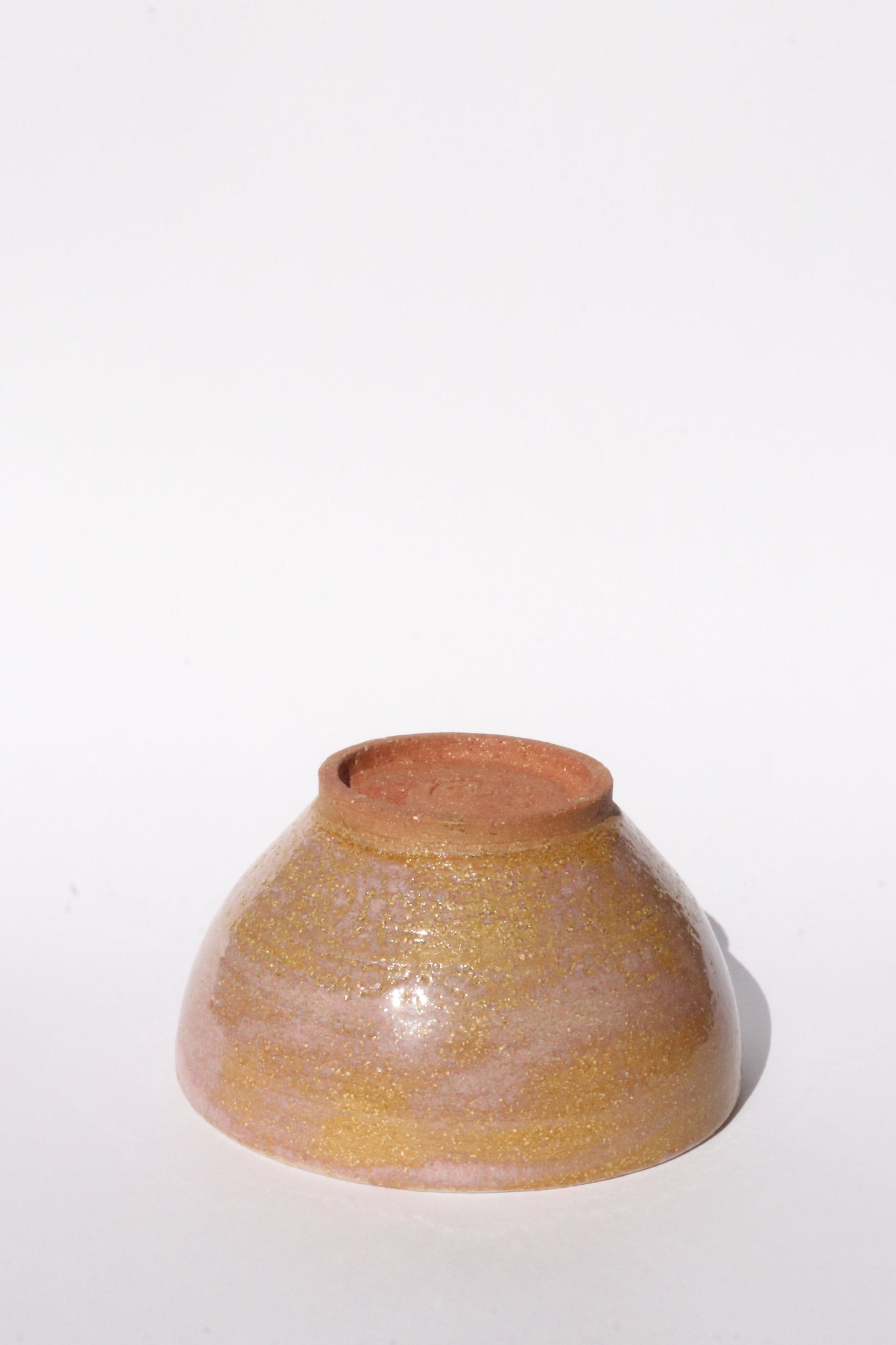 Ceramic brown and pink bowl turned upside down on a white background