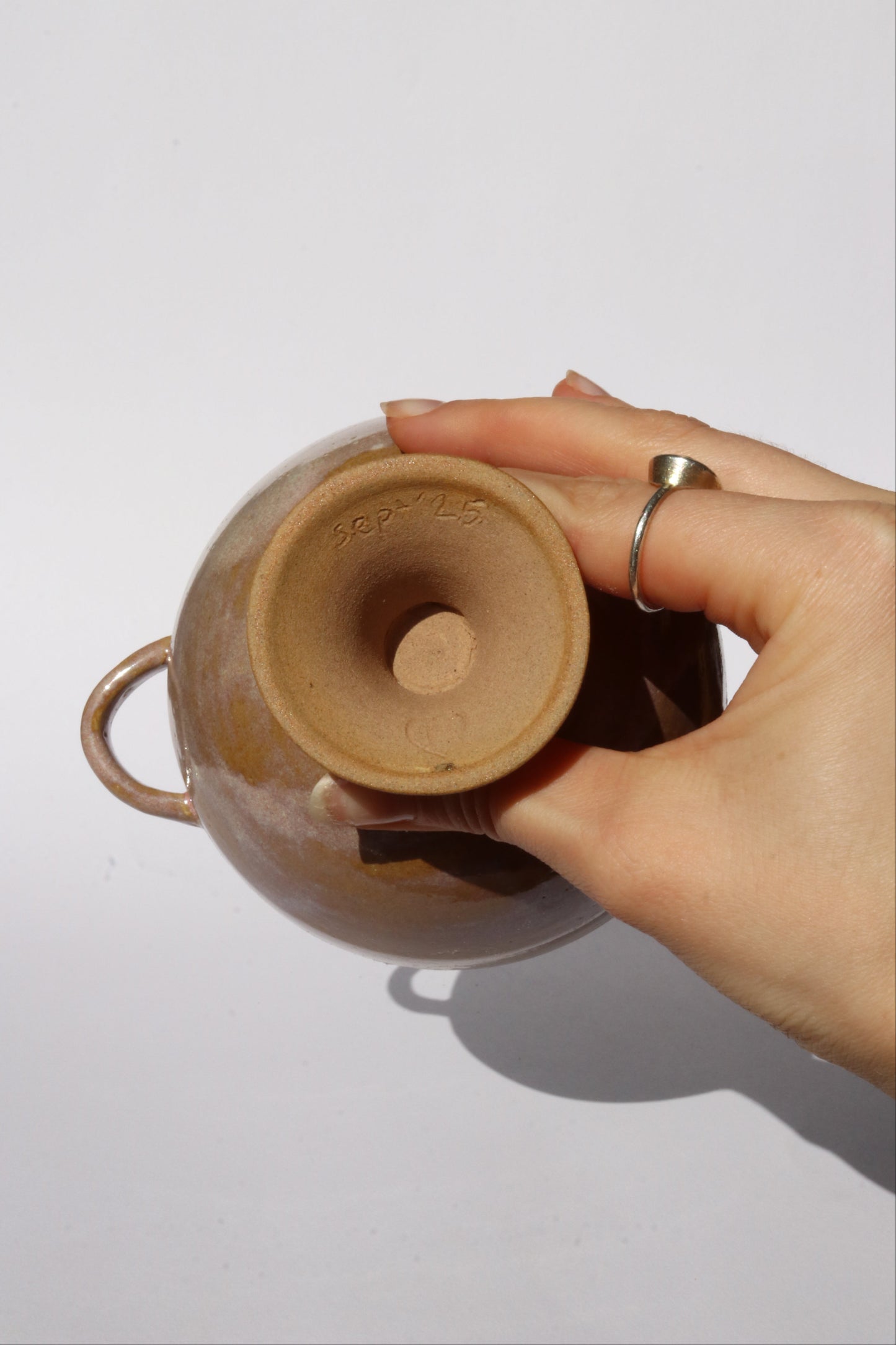 Hand holding a ceramic footed bowl with a plain background
