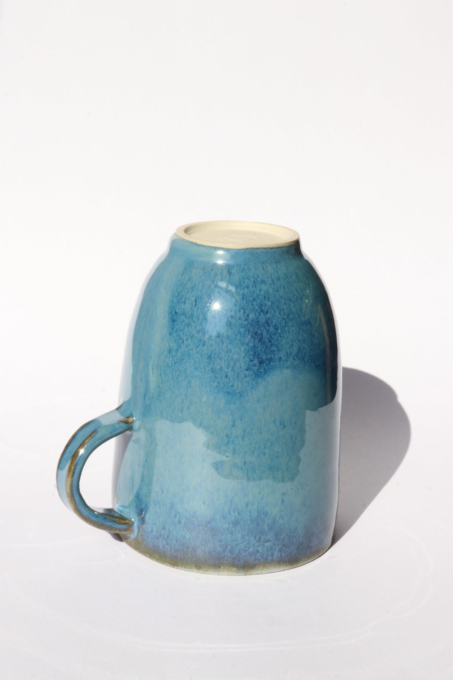 Upside down dark blue ceramic mug on a white background