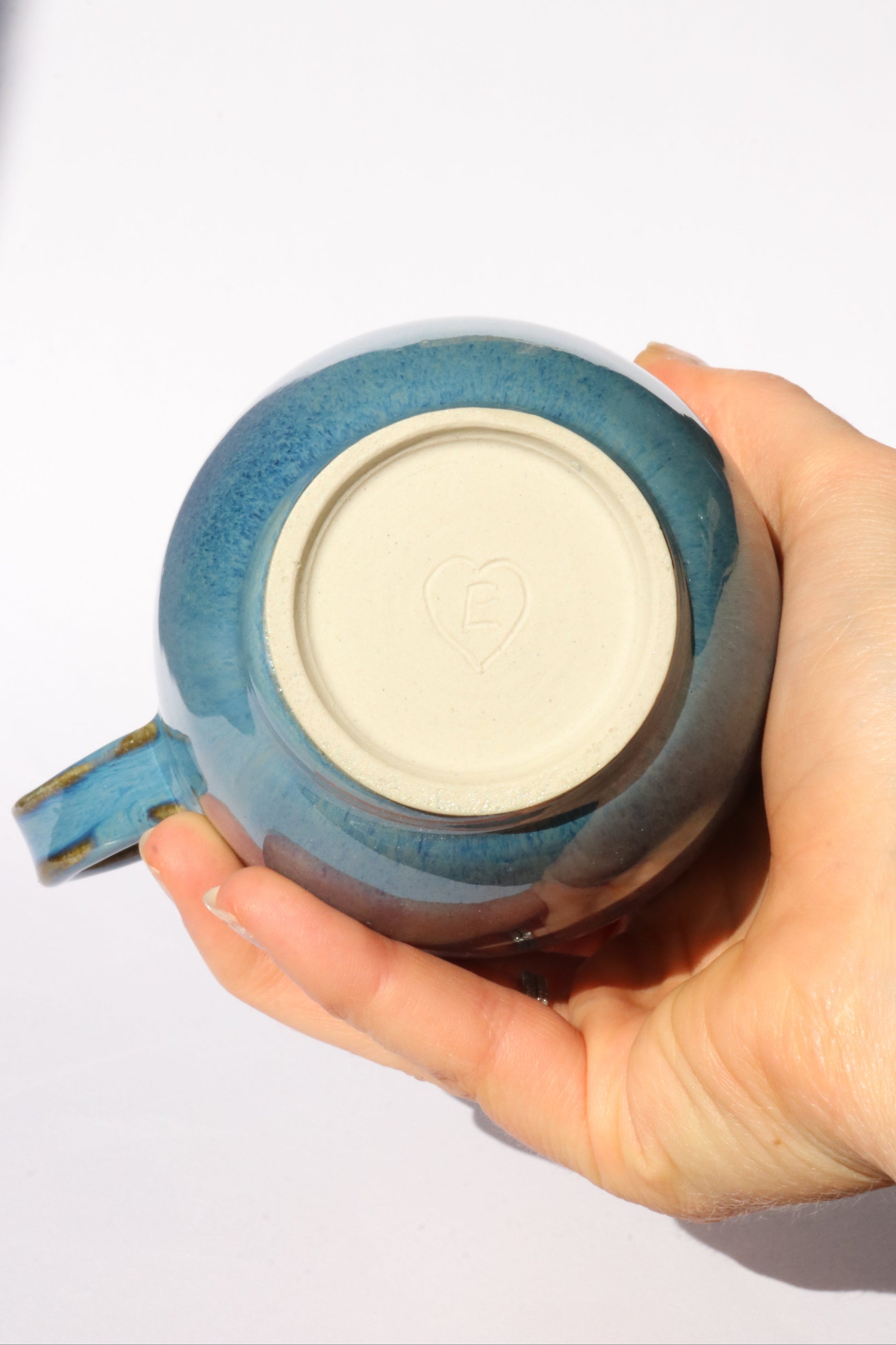 Hand holding a dark blue ceramic mug against a white background
