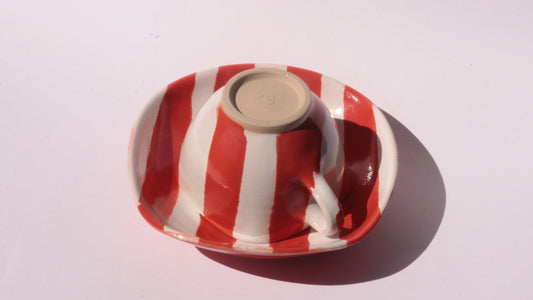 red and white striped ceramic cup and saucer on white background