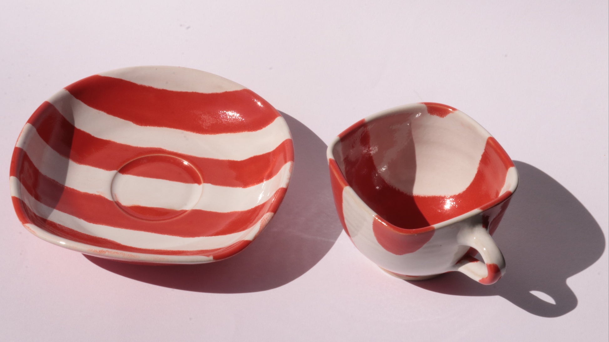 red and white striped ceramic cup and saucer on white background