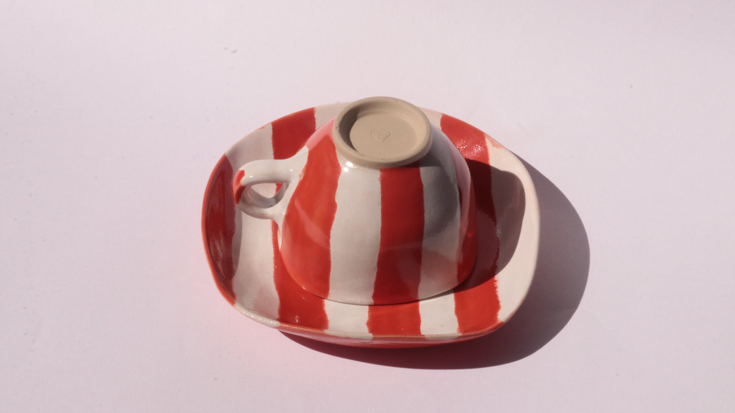 Ceramic cup and saucer with red and white stripe on a white background