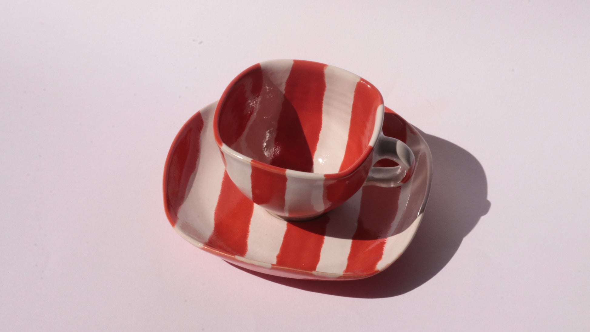 Ceramic cup and saucer with red and white stripe on a white background