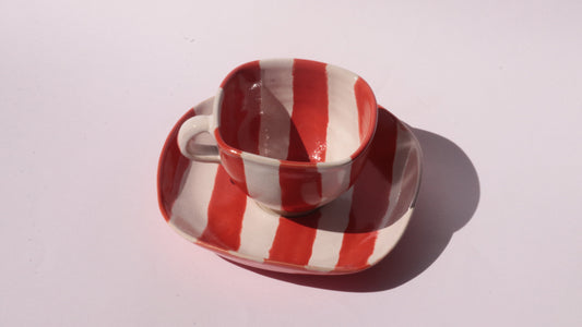 Ceramic cup and saucer with red and white stripe on a white background