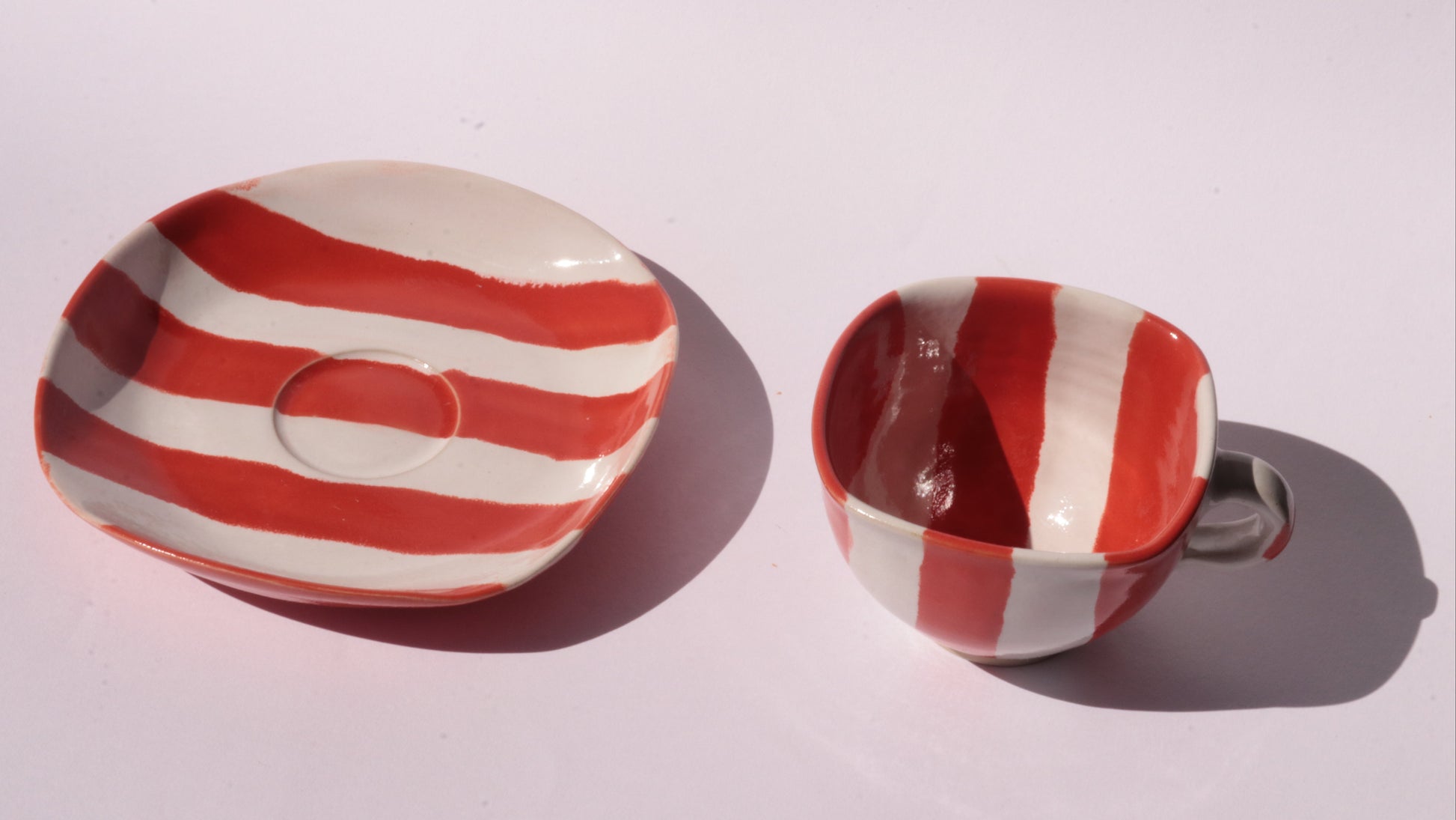 Ceramic cup and saucer with red and white stripe on a white background