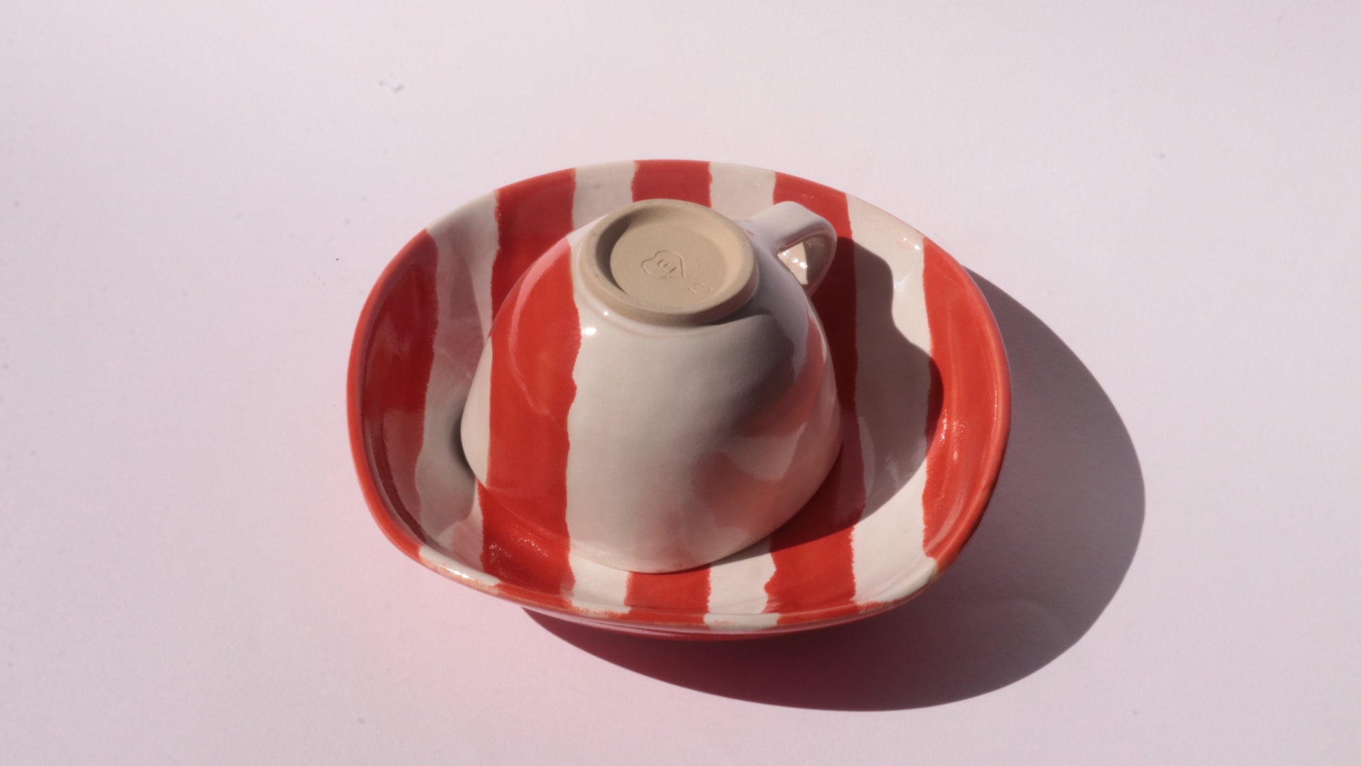 Ceramic cup and saucer with red and white stripes on a white background