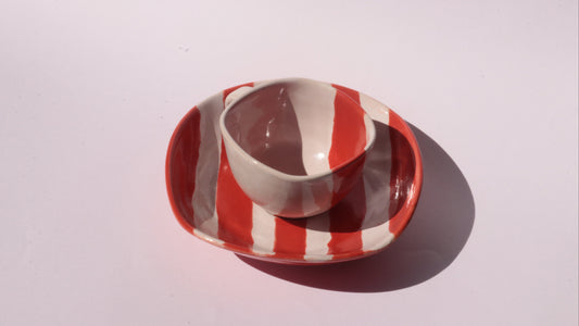Ceramic cup and saucer with red and white stripes on a white background