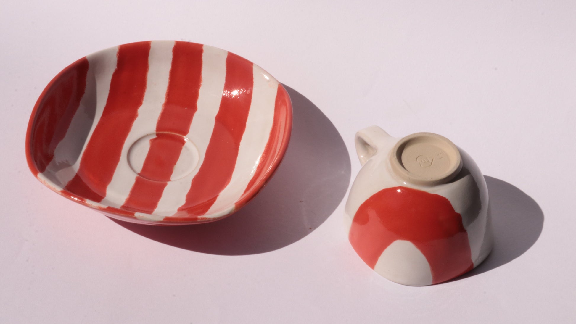 Ceramic cup and saucer with red and white stripes on a white background