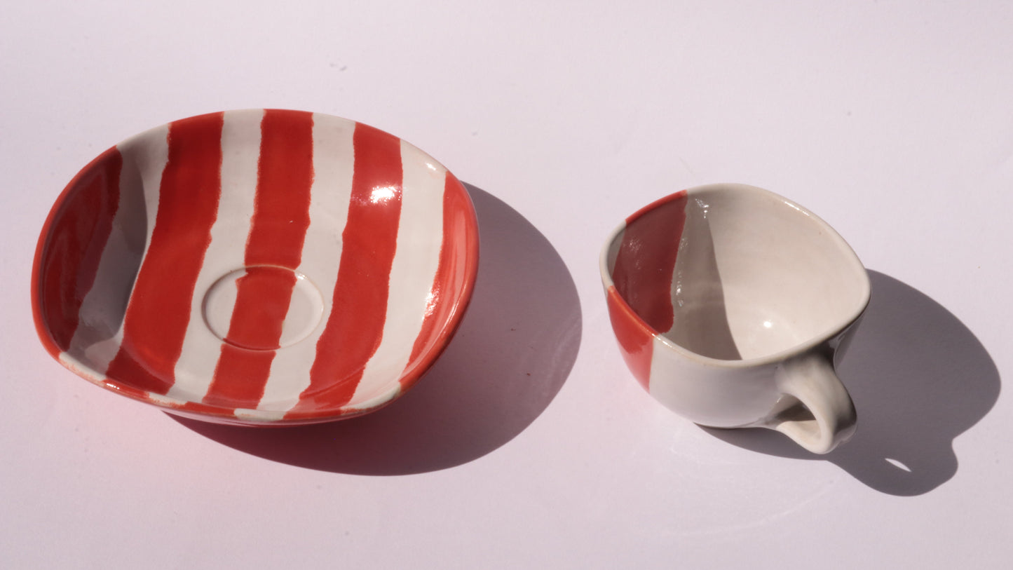 Ceramic cup and saucer with red and white stripes on a white background