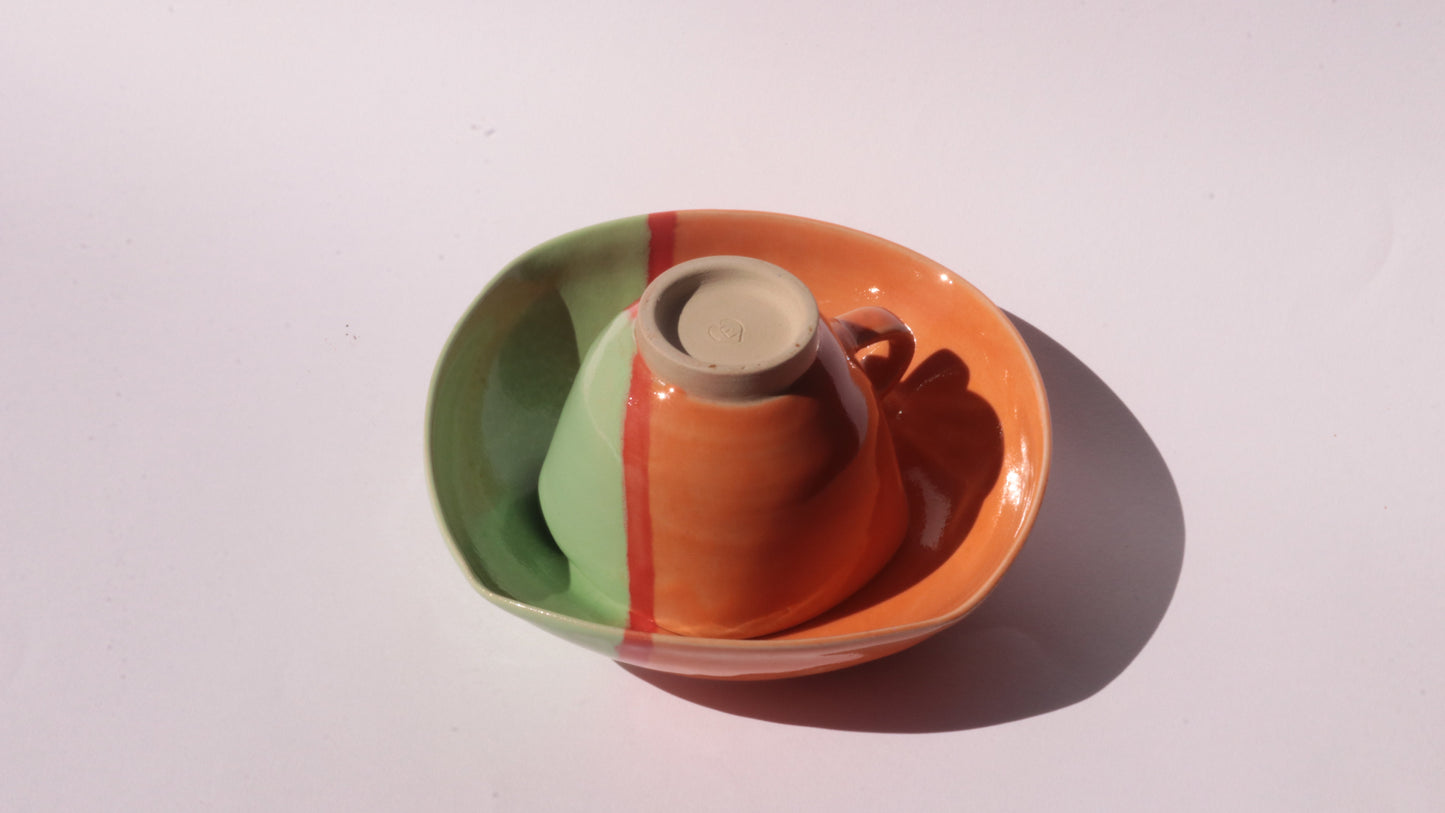 Ceramic cup and saucer with a colorful design on a white background