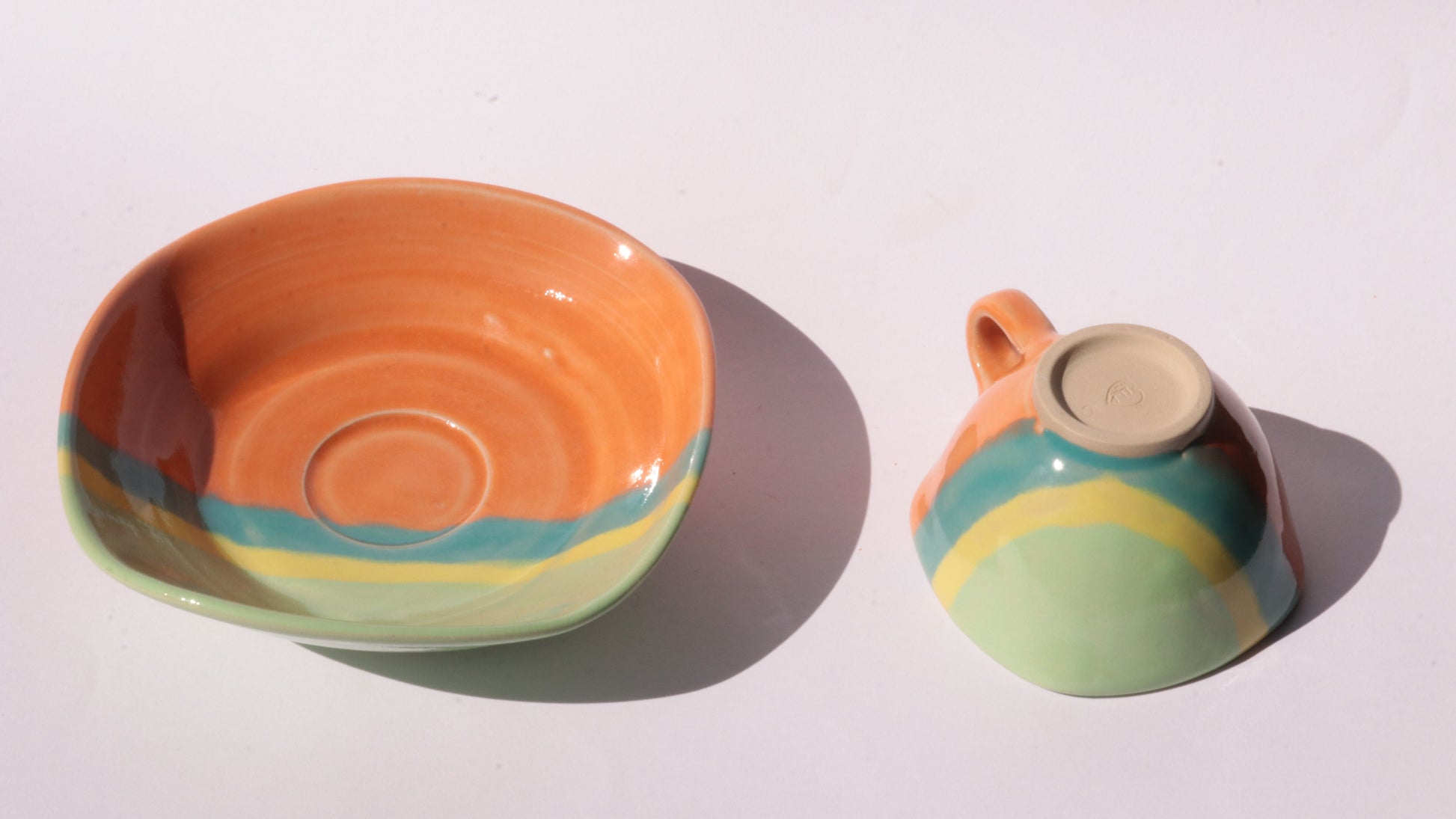 ceramic cup and plate with multicolored patterns on a white background