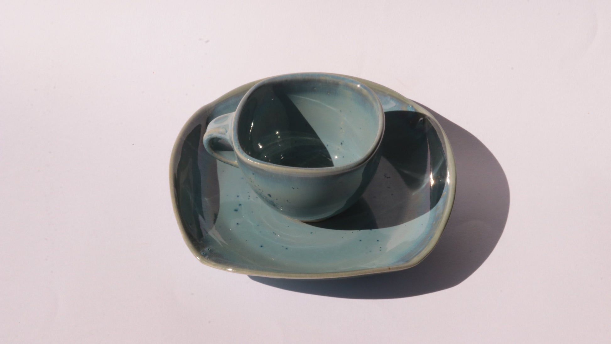 Blue coffee cup and saucer with square rims on white background