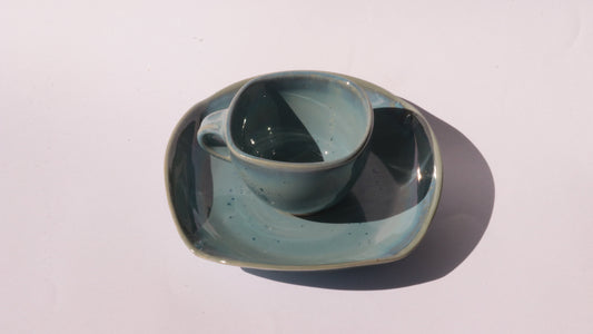 Blue coffee cup and saucer with square rims on white background
