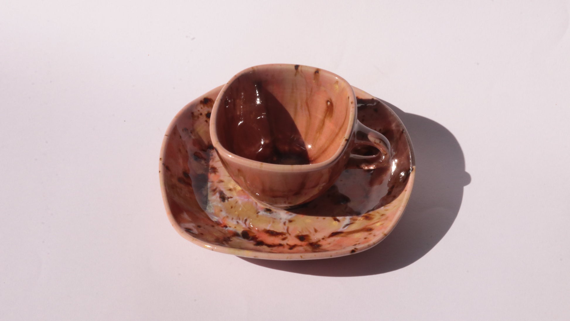 Orange and Pink coffee cup and saucer with square rims on white background