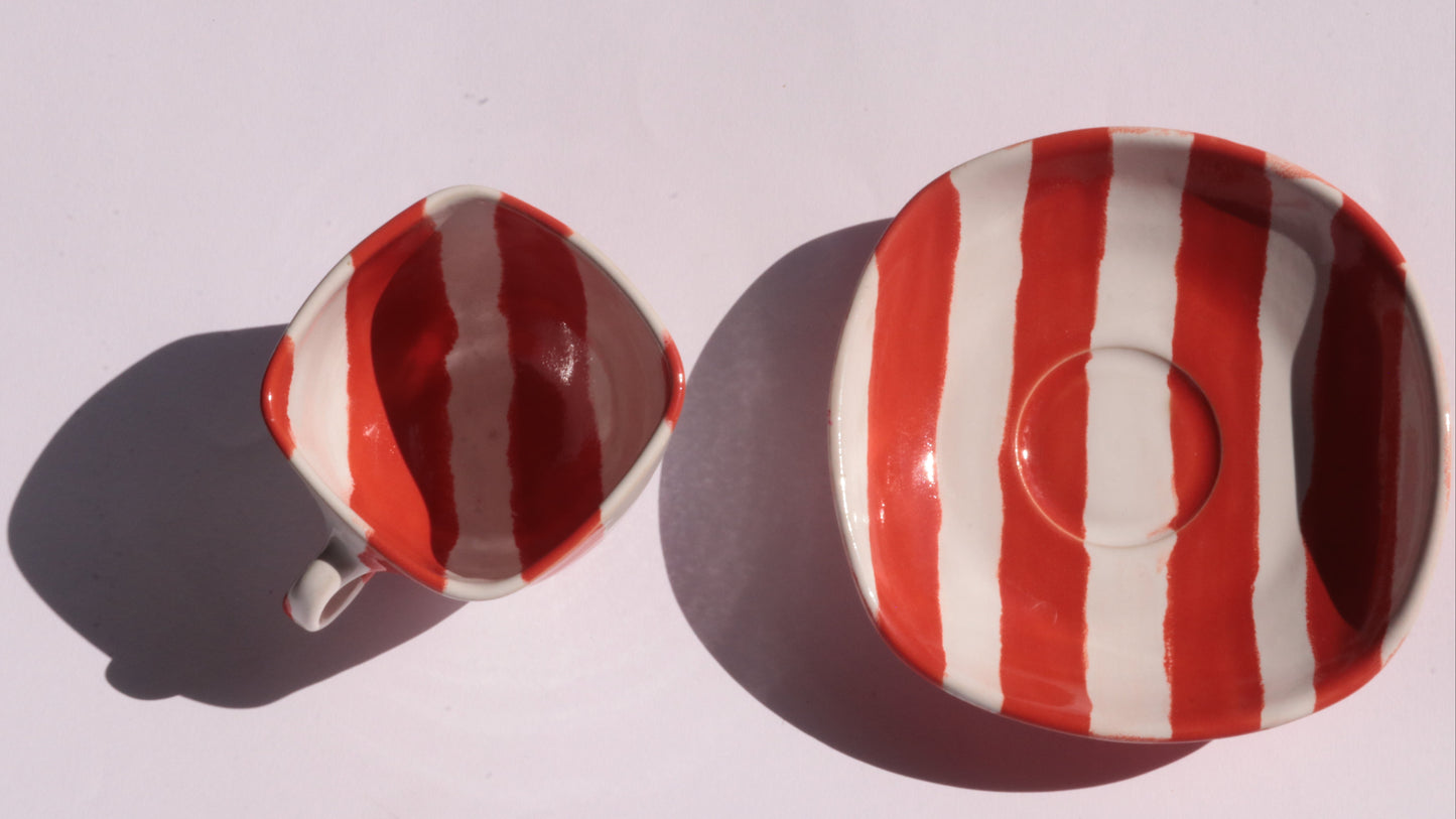 red and white striped ceramic cup and saucer on white background