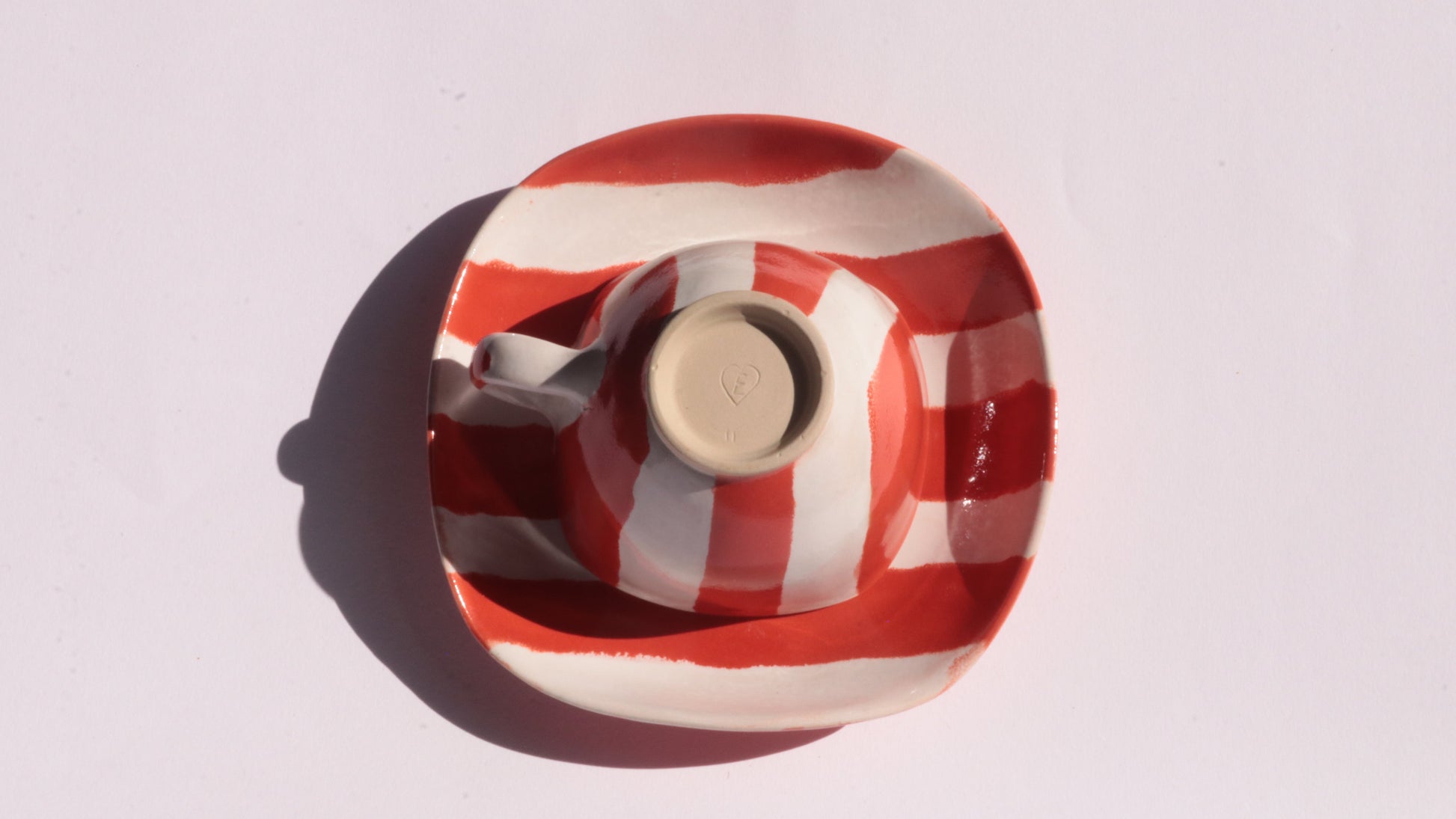 Ceramic cup and saucer with red and white stripe on a white background