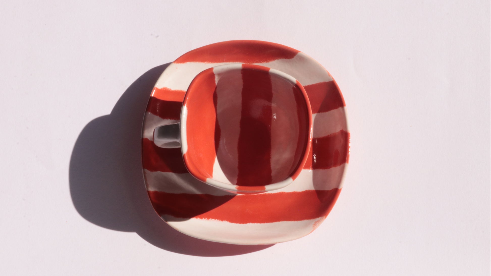 Ceramic cup and saucer with red and white stripe on a white background