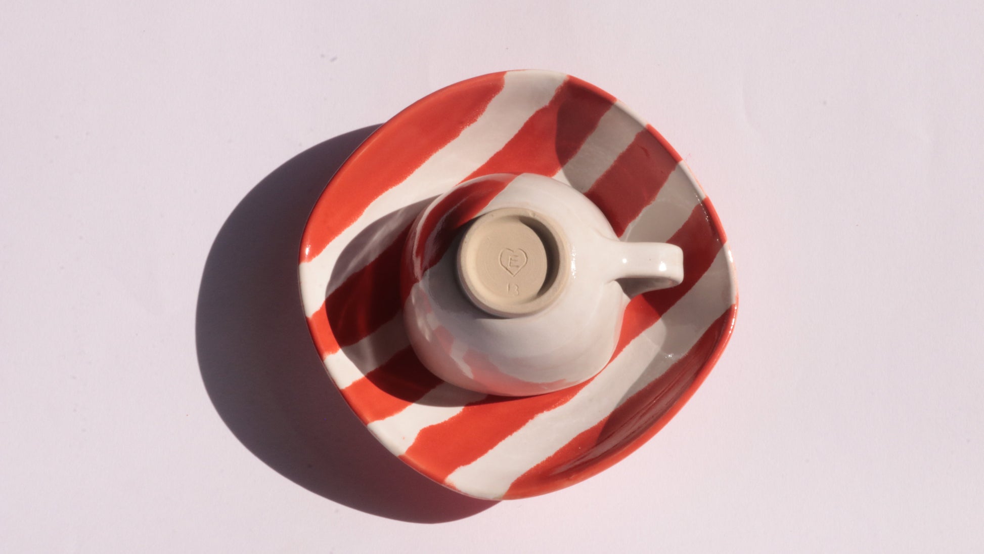 Ceramic cup and saucer with red and white stripes on a white background