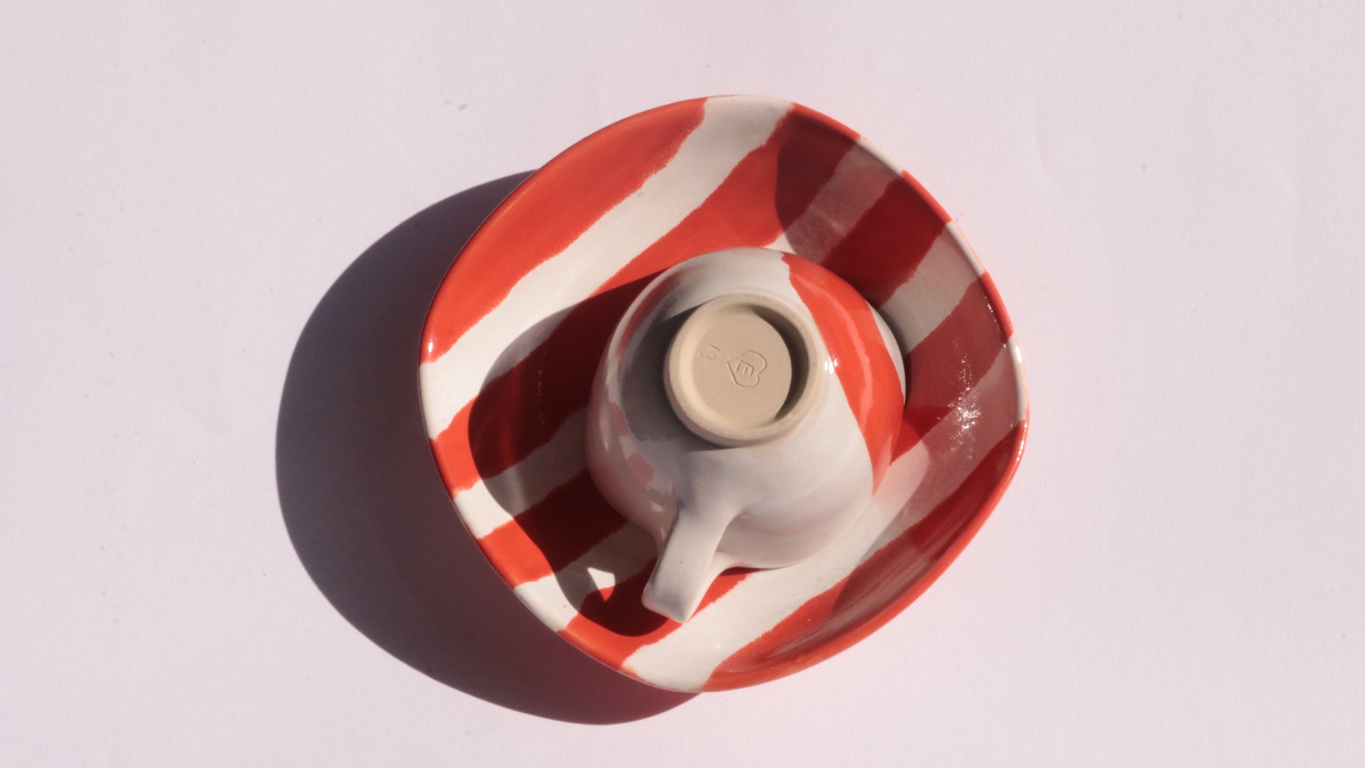 Ceramic cup and saucer with red and white stripes on a white background