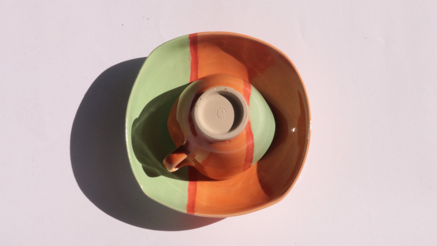 Ceramic plate and cup green, orange and red design on a white background
