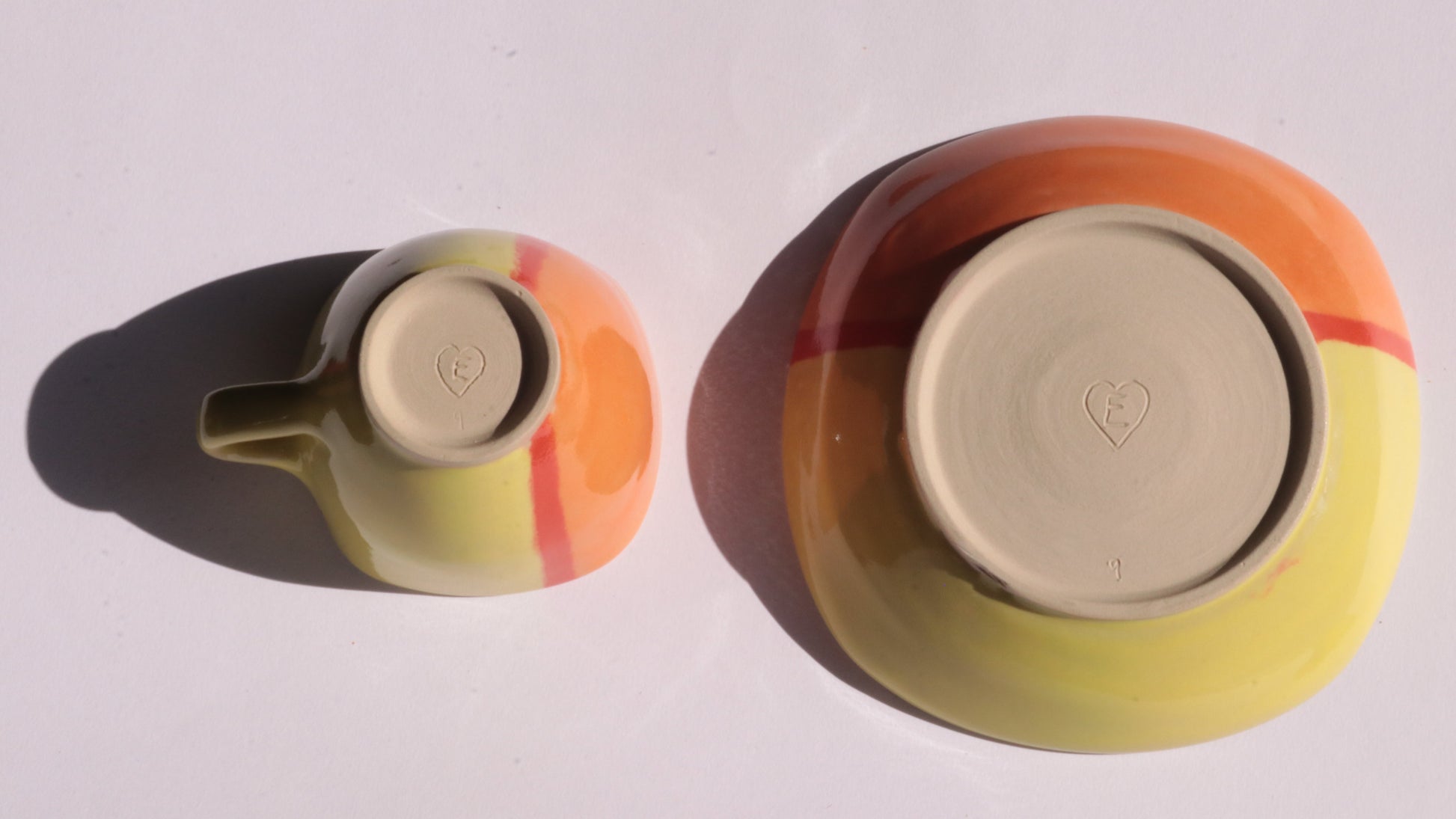 ceramic cup and saucer turned upside down showing signature on a white background