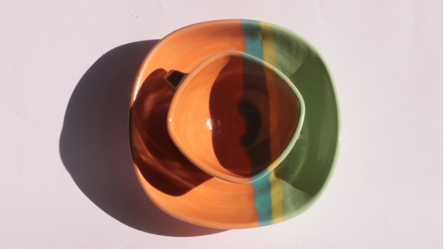 Colorful ceramic cup and saucer with a plain background