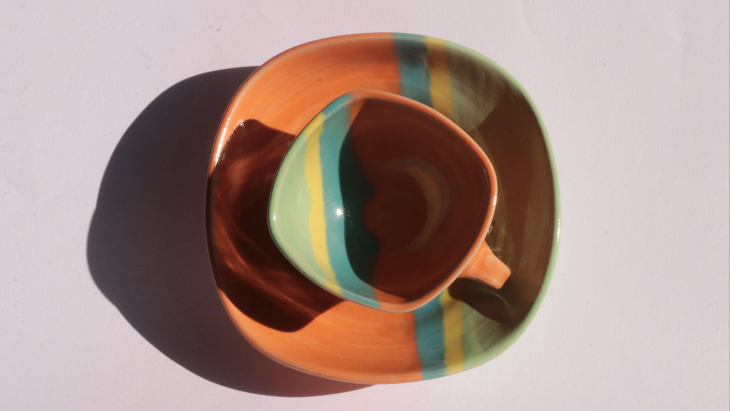 Colorful ceramic cup and saucer on a light gray background