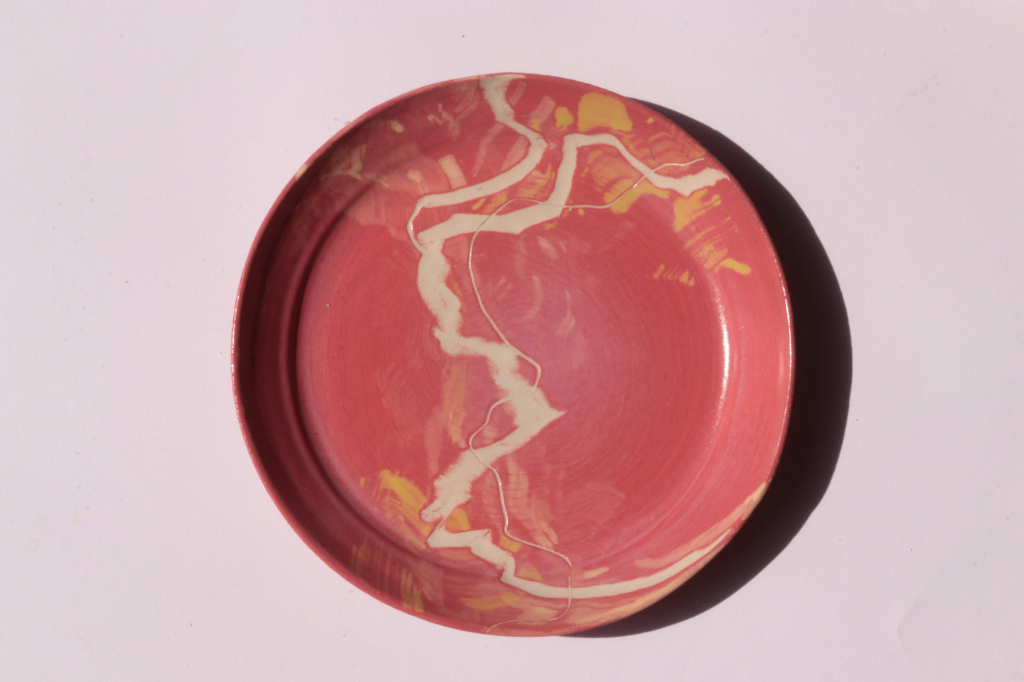 Round red plate with white and yellow engraved design on a light gray background