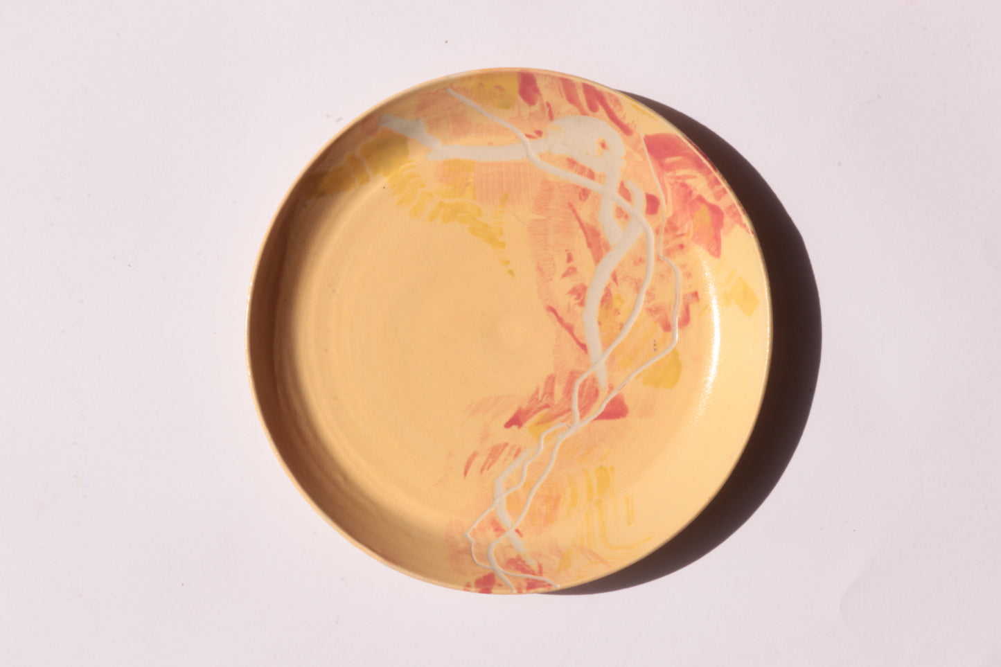 Yellow red plate with white and yellow engraved design on a light gray background
