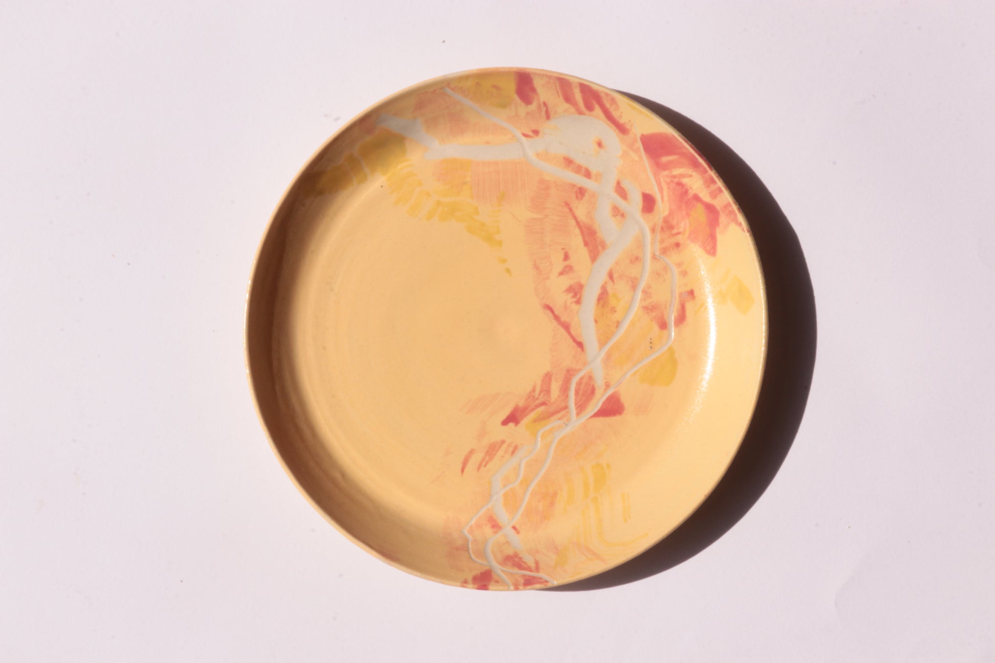 Yellow red plate with white and yellow engraved design on a light gray background