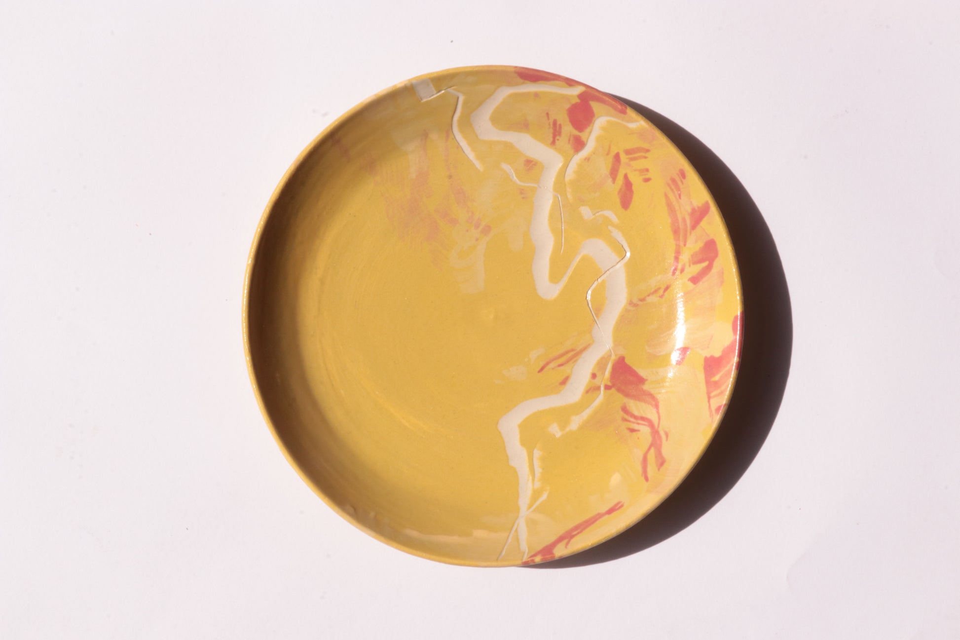 Round green plate with white and yellow engraved design on a light gray background
