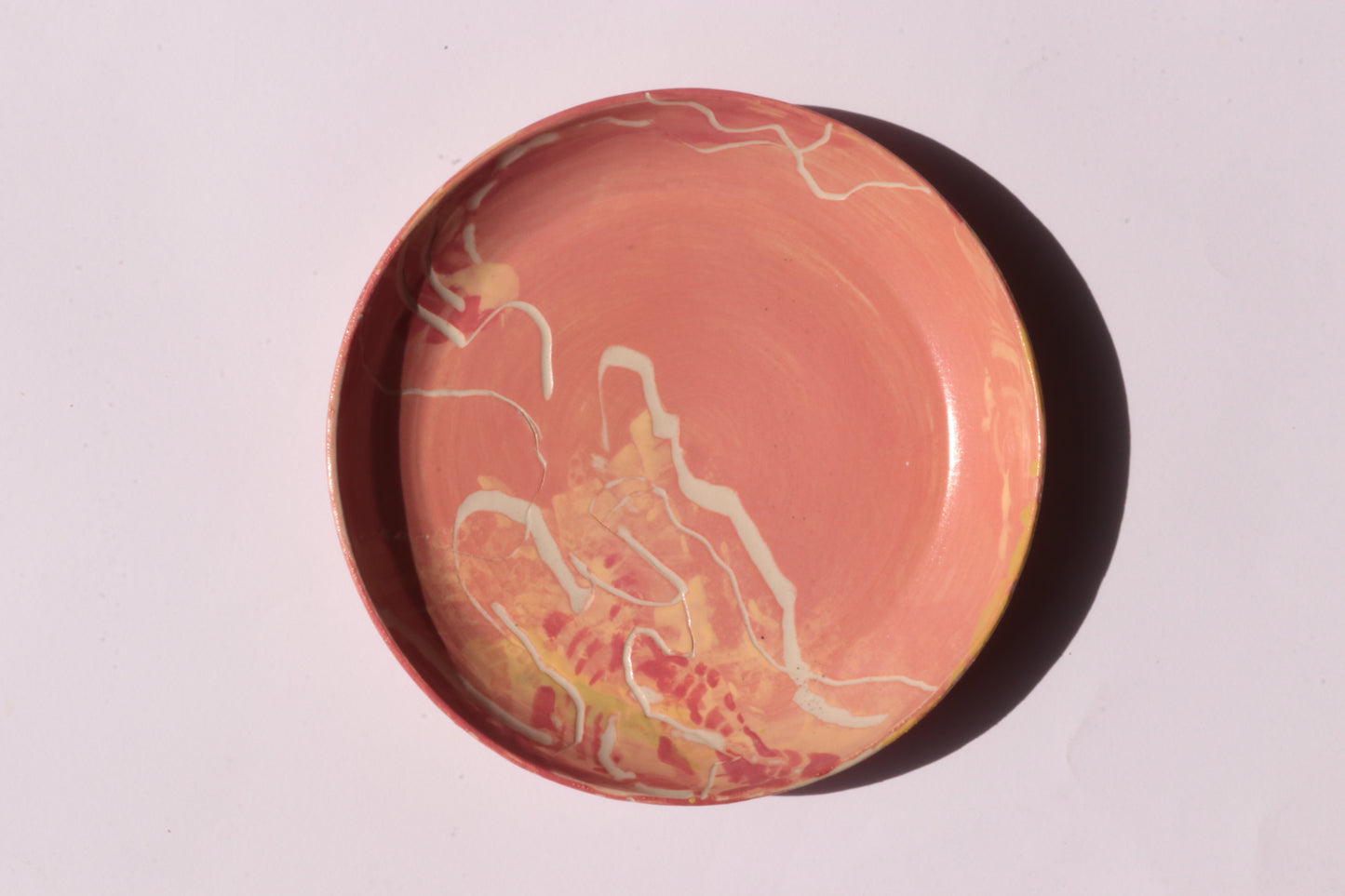 Round orange plate with white and yellow engraved design on a light gray background