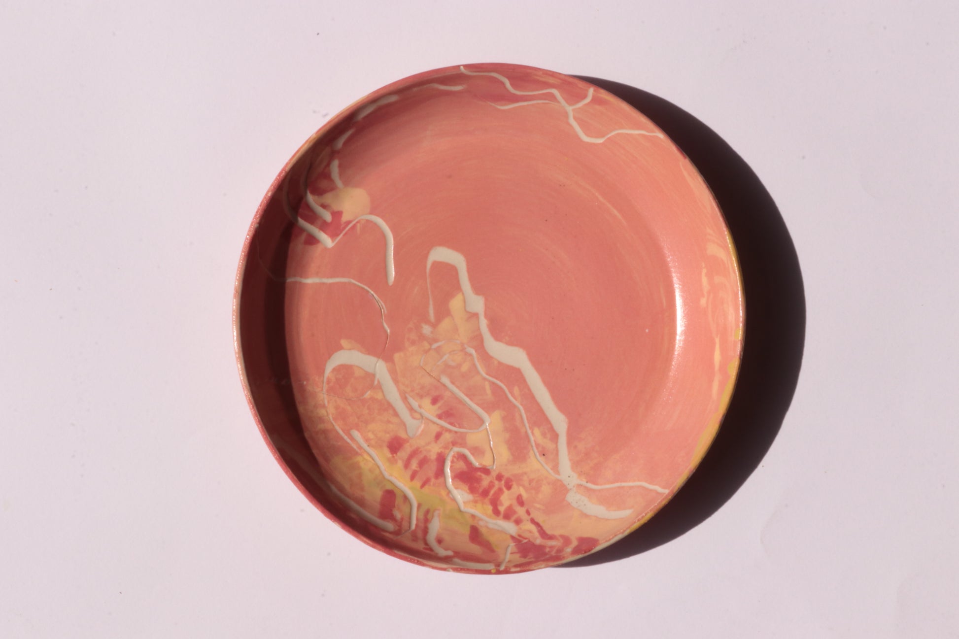 Round orange plate with white and yellow engraved design on a light gray background