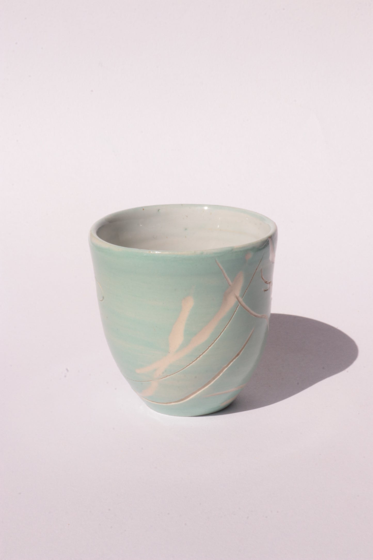 engraved light blue ceramic cup on white background