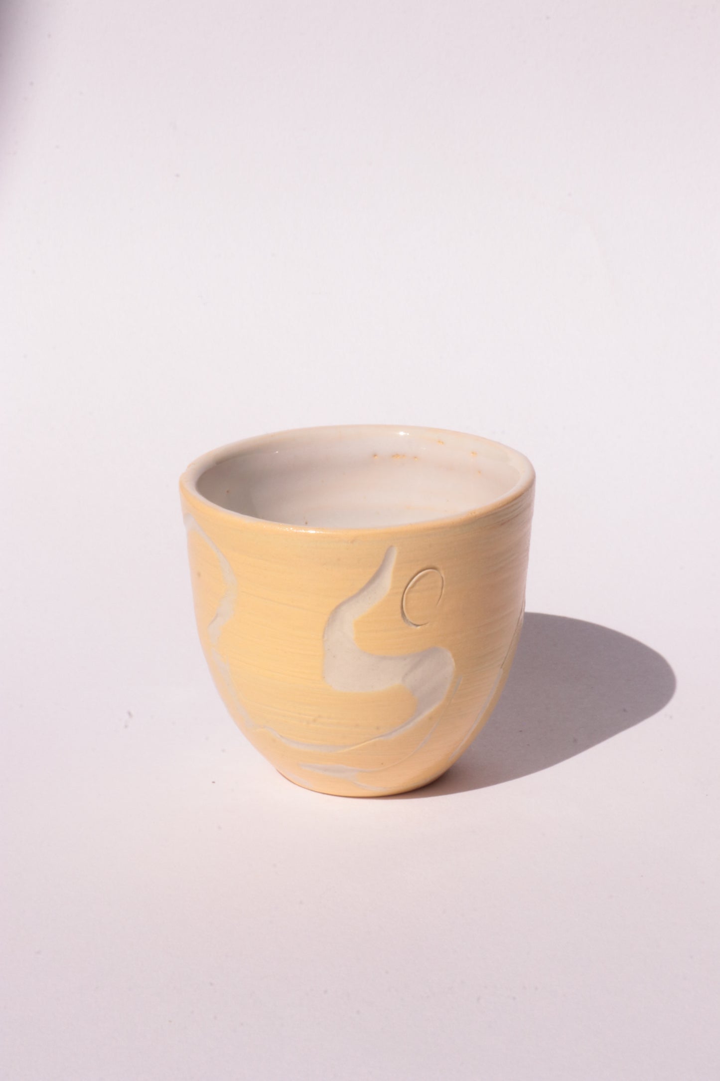 engraved yellow ceramic cup on white background
