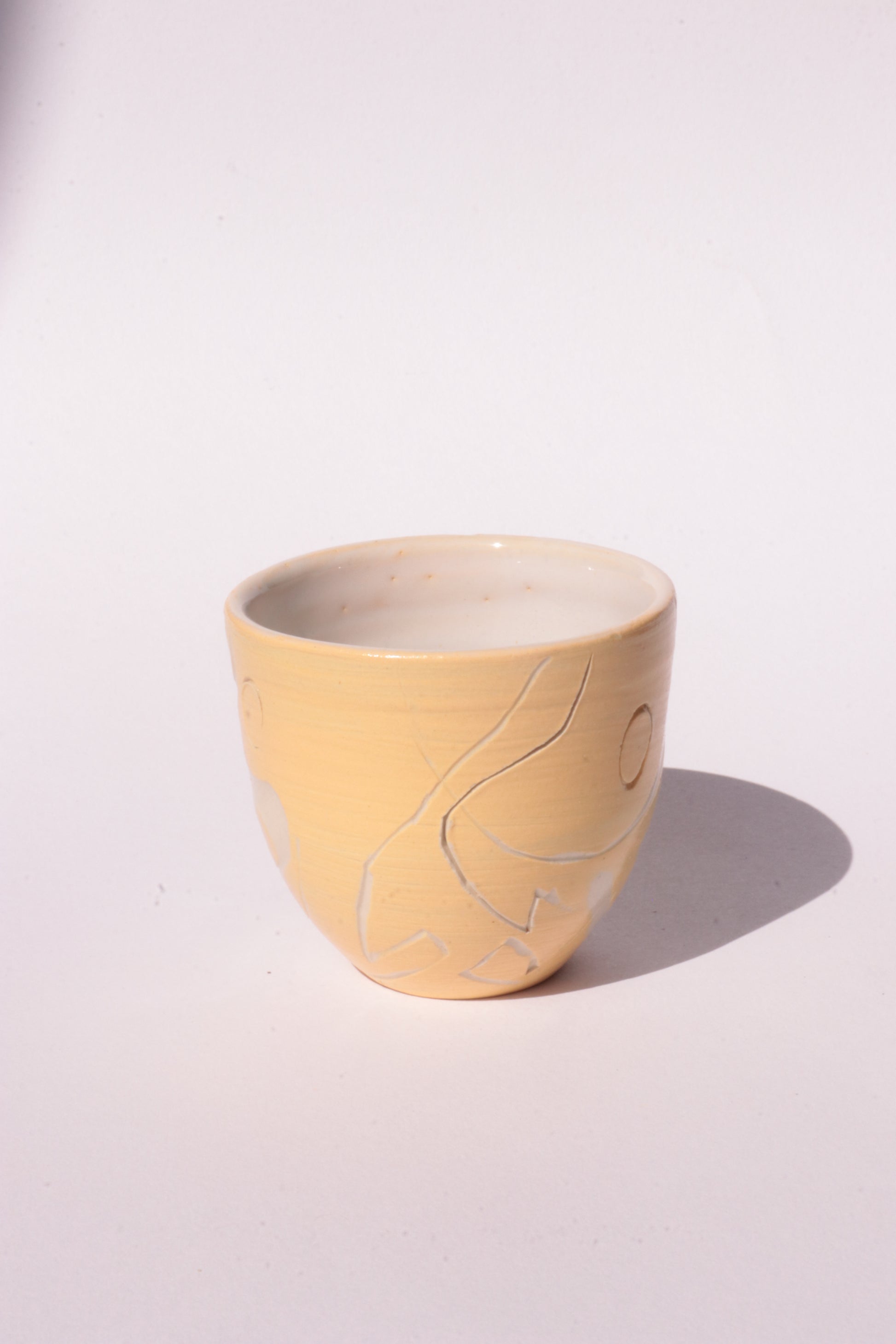 engraved yellow ceramic cup on white background