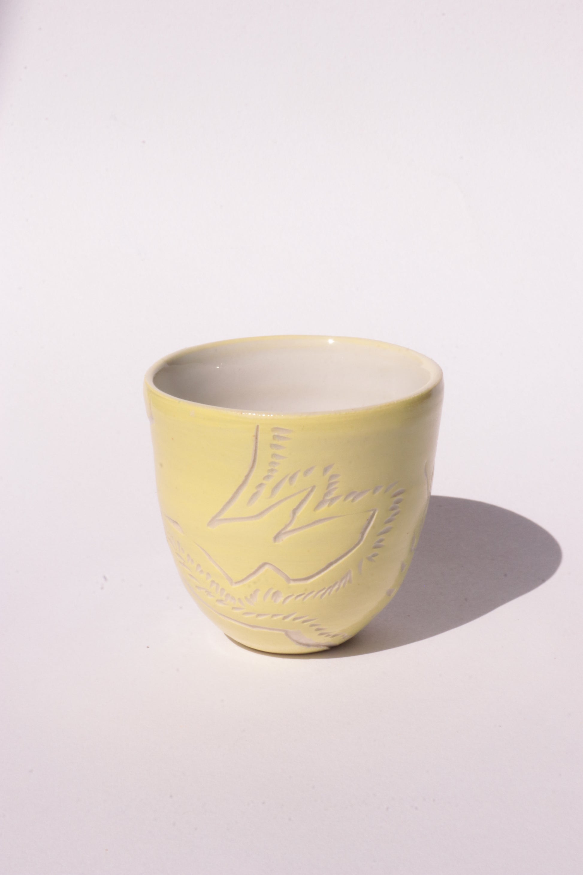 engraved yellow ceramic cup on white background