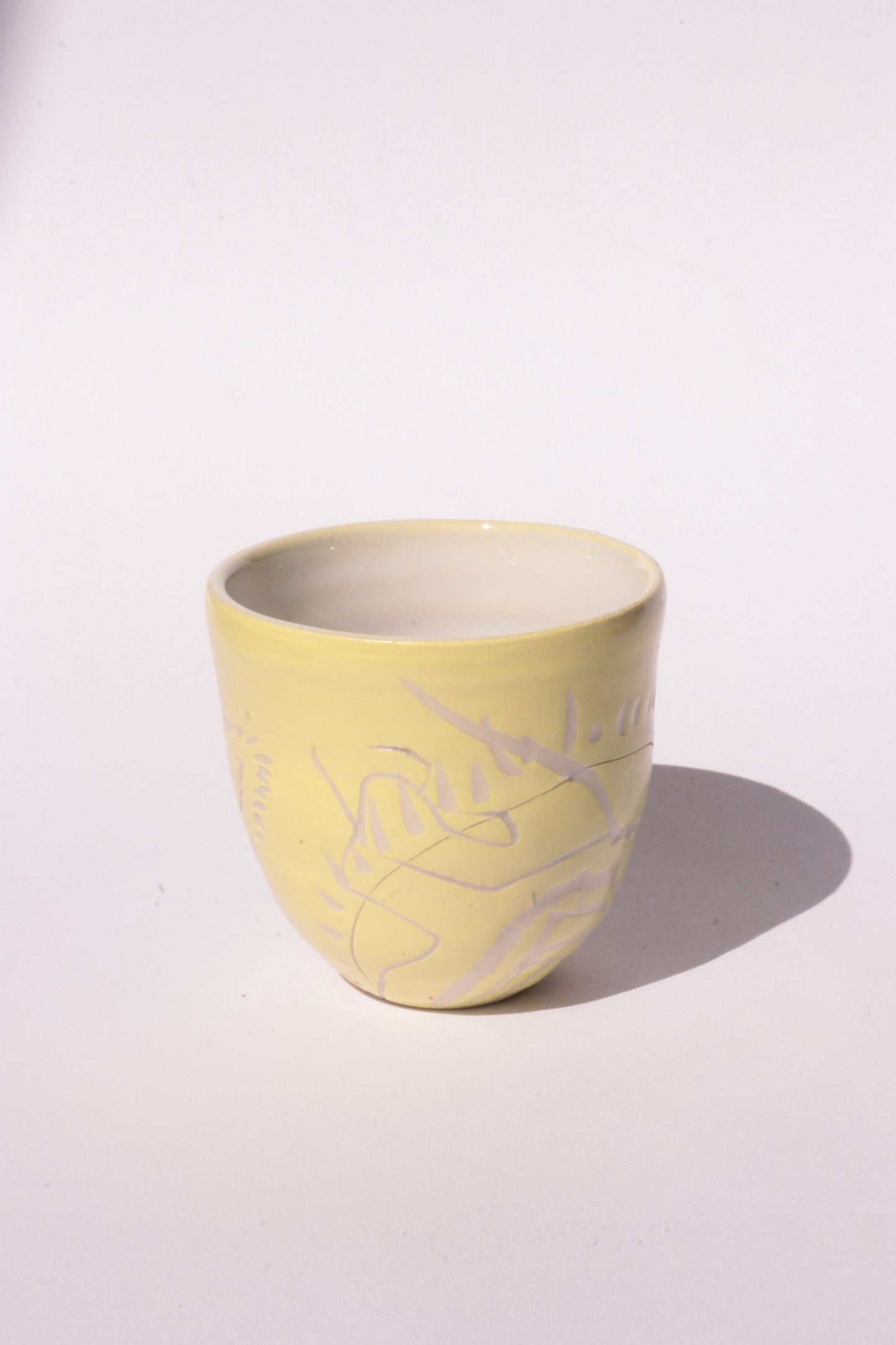 engraved yellow ceramic cup on white background