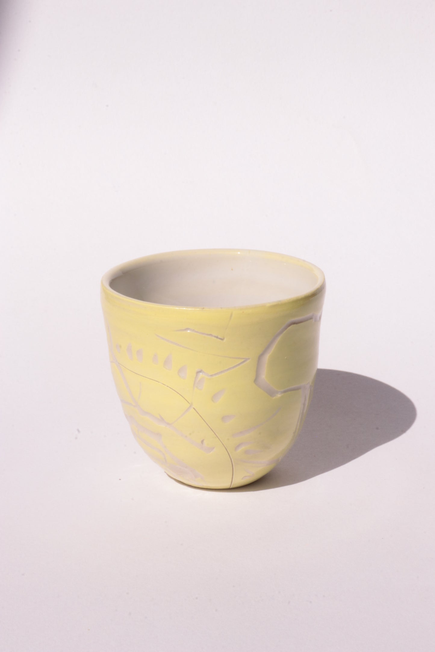 engraved yellow ceramic cup on white background