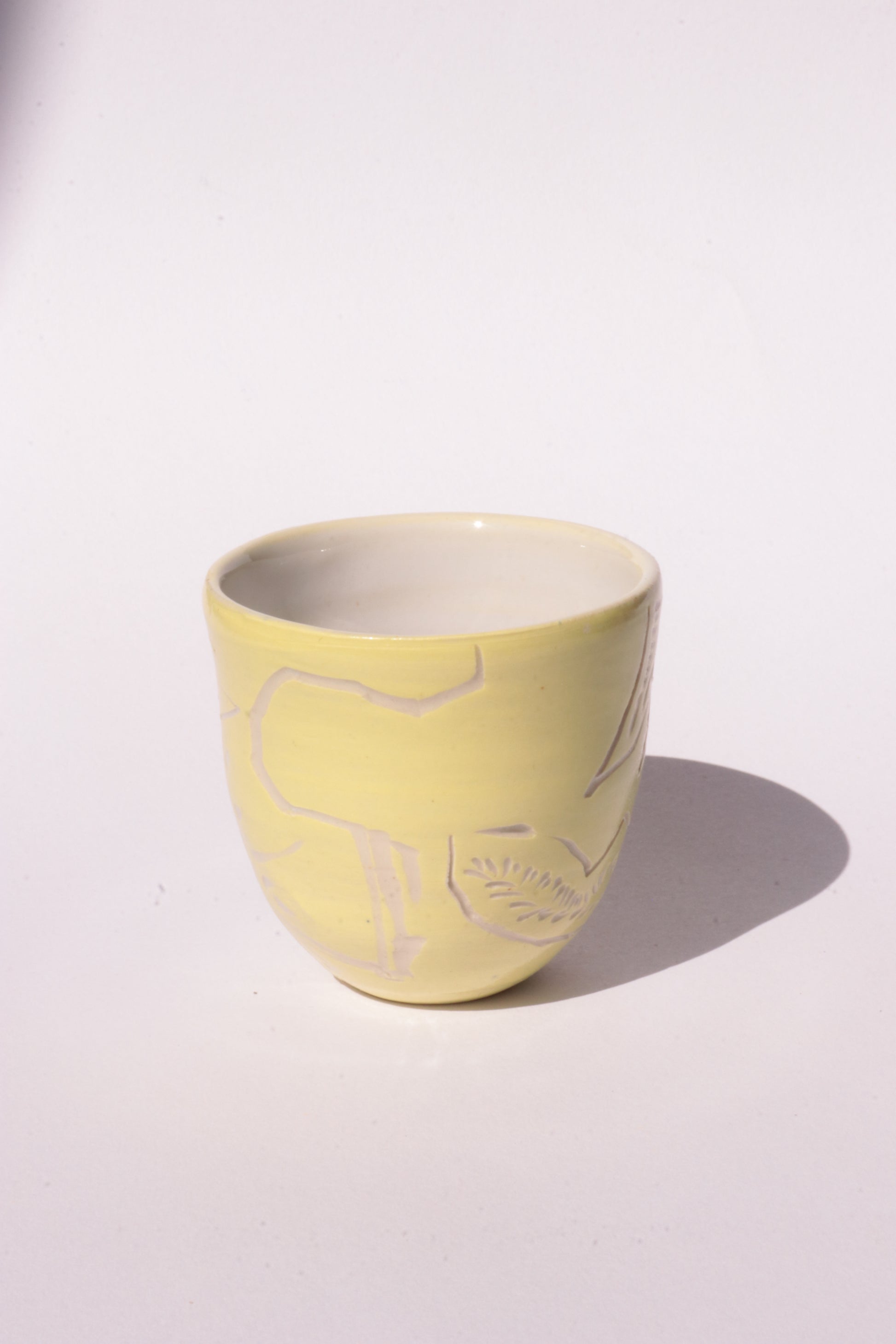 engraved yellow ceramic cup on white background