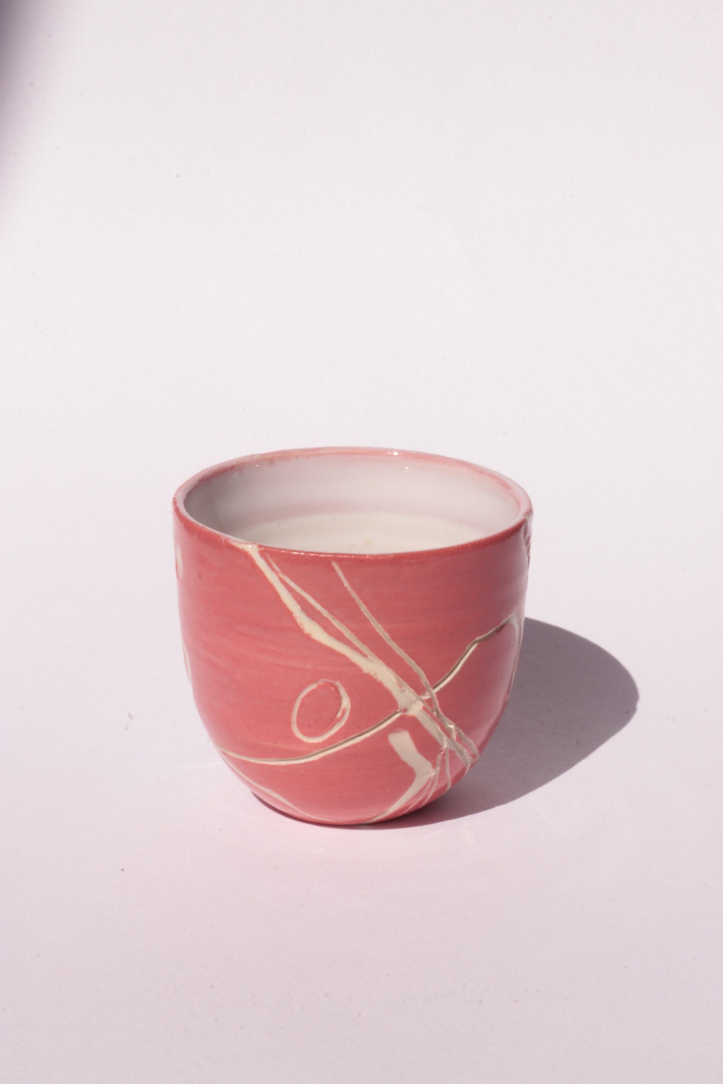 engraved magenta ceramic cup on white background