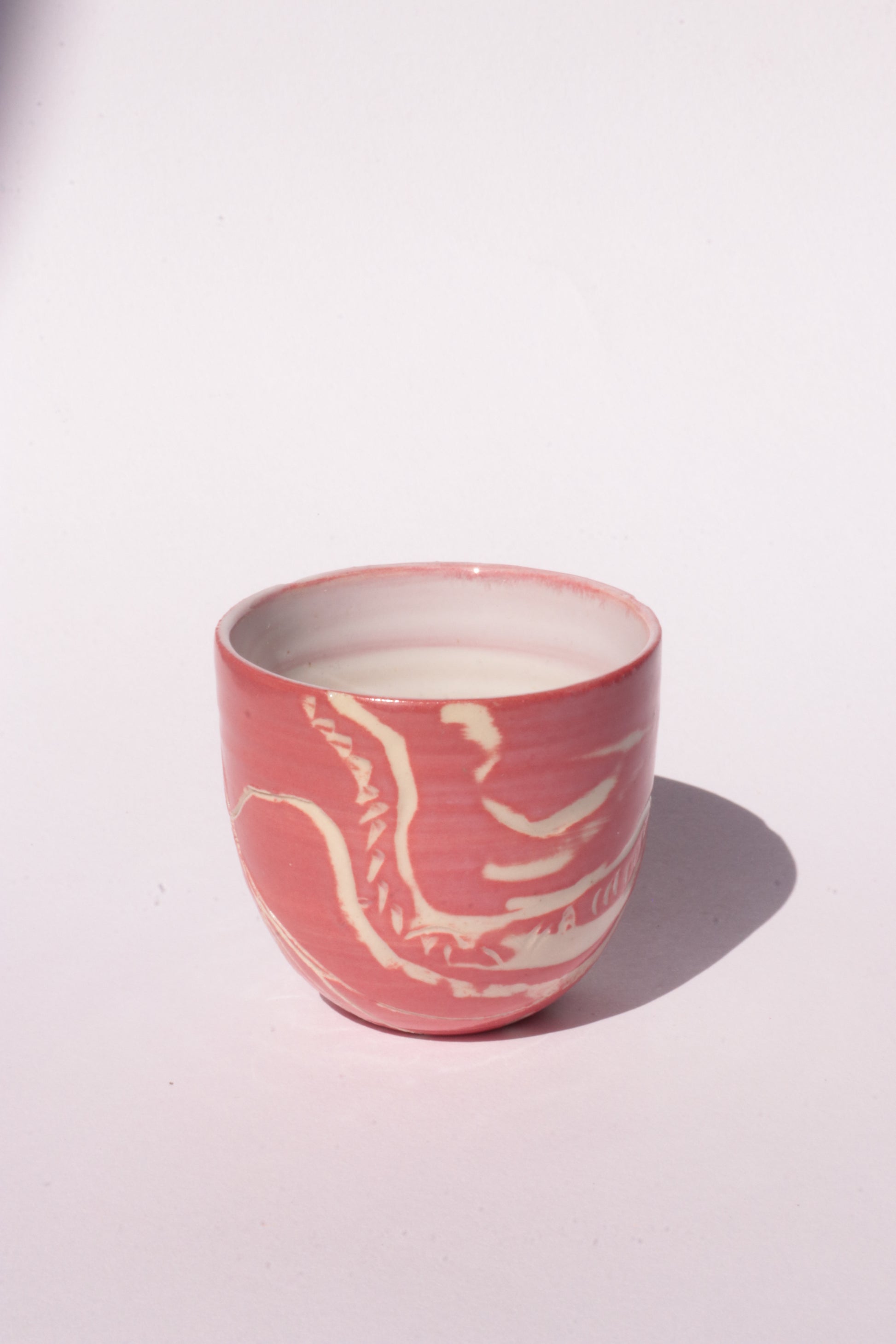 engraved magenta ceramic cup on white background