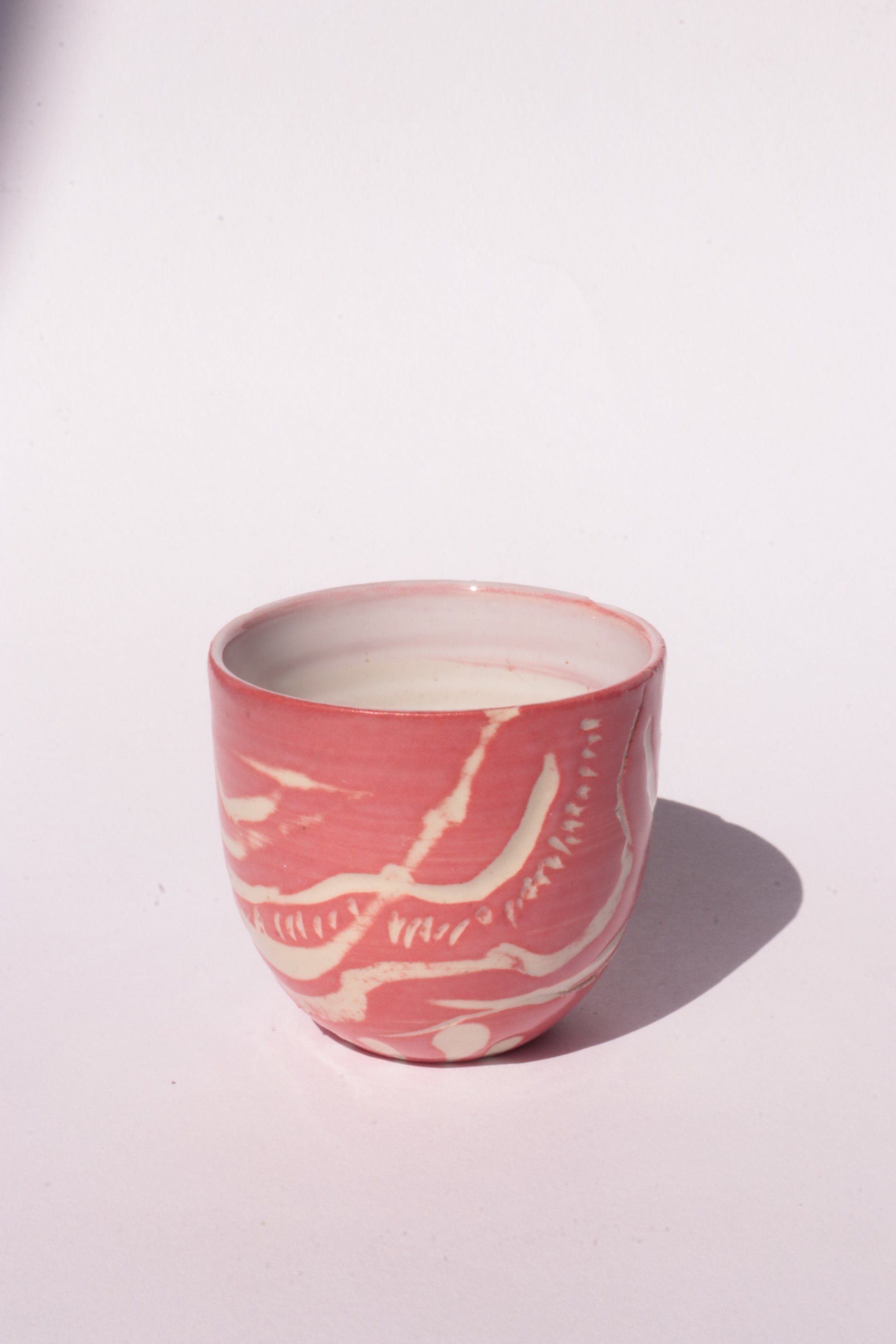 engraved magenta ceramic cup on white background